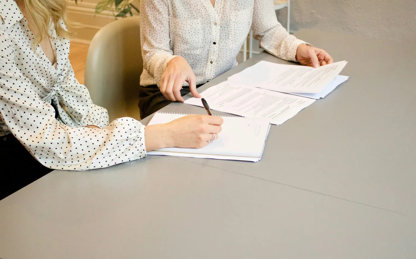 woman signing on white printer paper beside woman about to touch the documents by Gabrielle Henderson courtesy of Unsplash.
