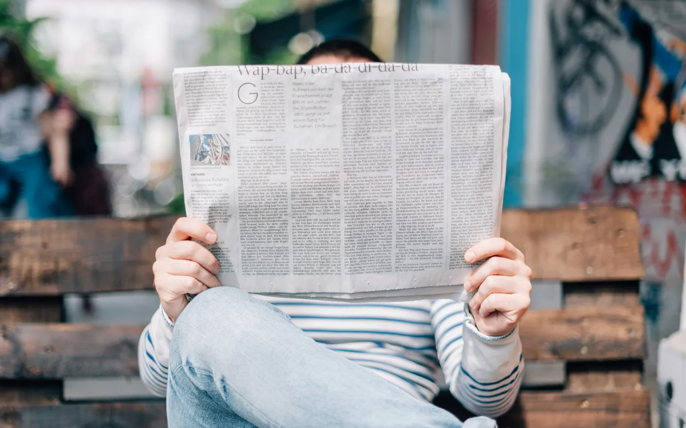 man sitting on bench reading newspaper by Roman Kraft courtesy of Unsplash.