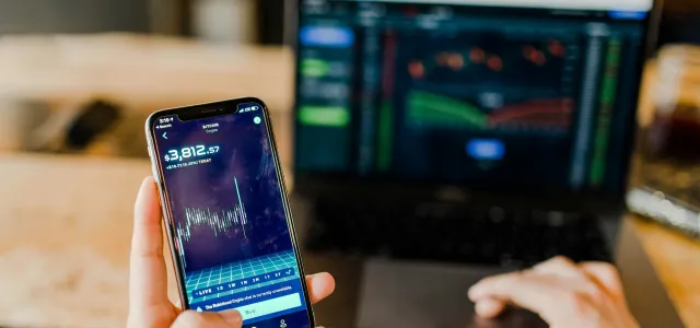 person using phone and laptop computer by Austin Distel courtesy of Unsplash.