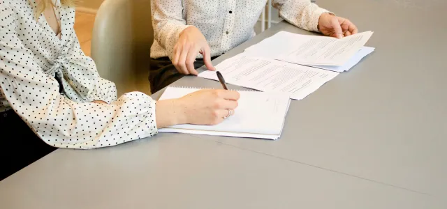 woman signing on white printer paper beside woman about to touch the documents by Gabrielle Henderson courtesy of Unsplash.